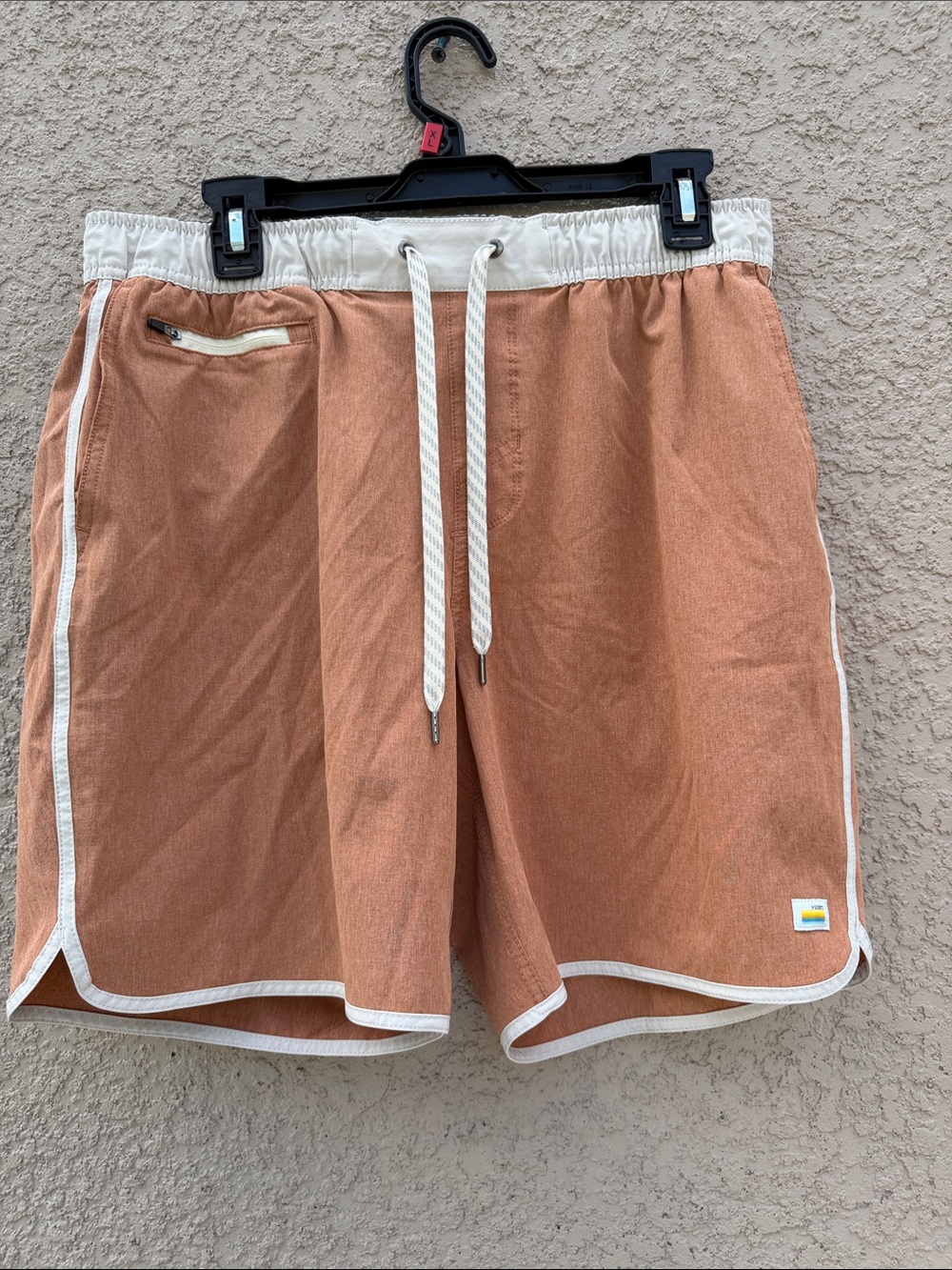 Vuori rust-orange athletic shorts with cream trim